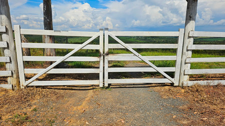 fence with white boards at the entrance to the farm, and plantations in the backgroundの写真素材