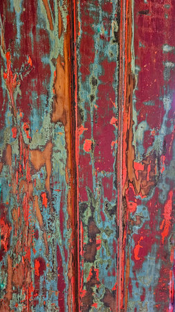 wooden door background painted in peeling red, with blue and orange accentsの写真素材
