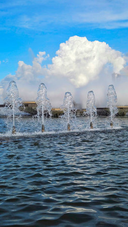 fountain with five spouts in an upward direction, in an urban fountain, with a blue sky in the backgroundの写真素材