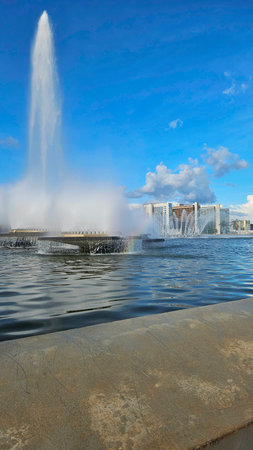 fountain with water jets, in a concrete lake, in an urban area, with buildings in the background and blue skyの写真素材