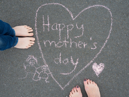 Mothers day - heart shape chalk drawing and the feet of a child and of a womanの写真素材