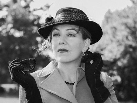 Vintage black and white portrait of a woman with a suit and a black hat looking dreamilyの写真素材