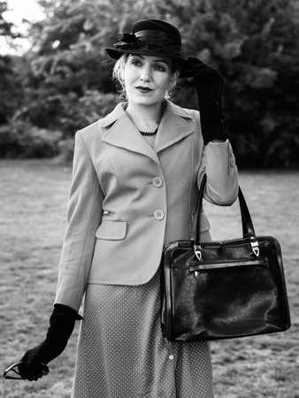 Vintage black and white  portrait of an old-fashioned attractive woman standing in the parkの写真素材