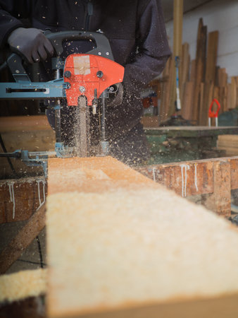 Close-up of the hands of a man with chain mortiser mill-cutting a wooden board