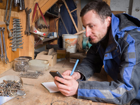 Portrait of young male carpenter calculating with smart-phoneの写真素材