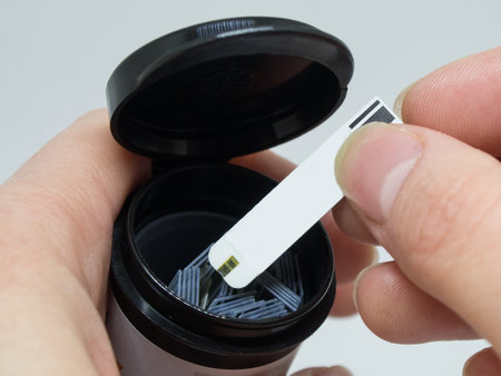 Close up of woman hands checking blood sugar level by Glucose meter using as Medicine, diabetes, glycemia, health care and people concept.の写真素材
