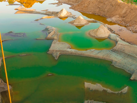 A view from above on a sandy quarry filled with water. photo from a drone. water is green. yellow...