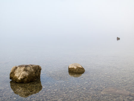 Two rocks and a duck in a misty lakeの写真素材