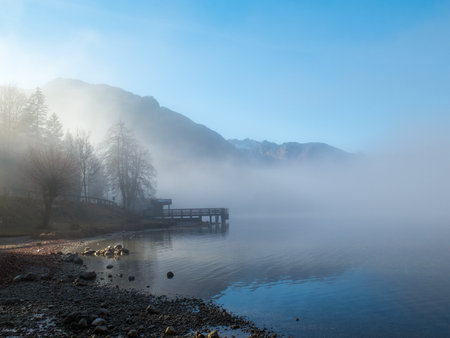 Pier in mist with trees and mountainsの写真素材