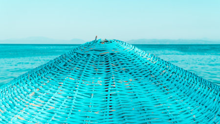 Wicker beach umbrella. Close-up of blue beach umbrella and sea on the background. Vacation concept background.の写真素材
