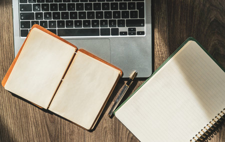 office desk. Laptop and notepad with blank page on wooden table high angle view. Office or study...