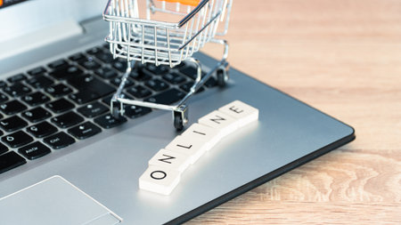 Online shopping concept. Shopping cart or trolley and laptop on wooden table.の写真素材