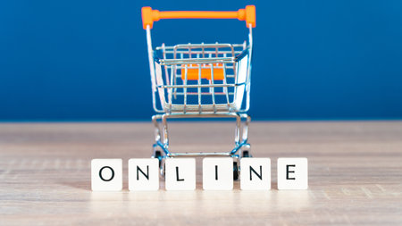 Online shopping concept. Shopping cart or trolley and laptop on wooden table.の写真素材