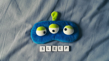 Sleeping mask and sleep icon on soft bed sheet. Bedtime concept. High angle view copy space for text