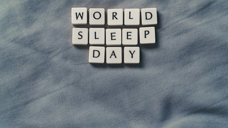 World Sleep Day concept with small lettered stones. Sleeping concept on a soft bed sheet. High angle...