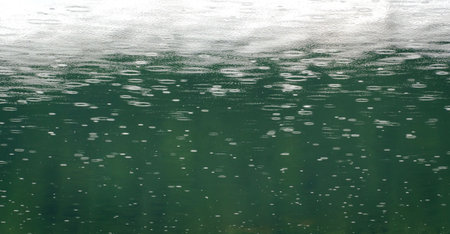 Raindrops on water surface. Raindrops falling on teal colored water. Minimal background.