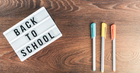 Back to school concept. School supplies on wooden background. Back to school lettering on white letter board. Copy space for text. Selective focus includedの写真素材