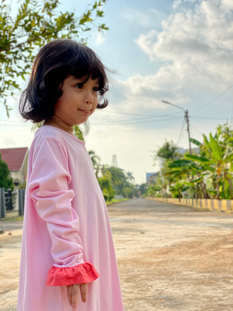 Portrait asian cute kid wearing pink dress standing outdoorの写真素材