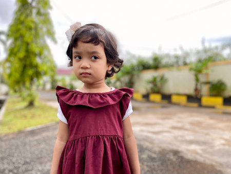 Portrait Kid wearing red dress in front of houseの写真素材