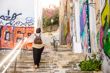 stylish young woman lifting throw a beautifull street stairs full of graffitiのeditorial素材