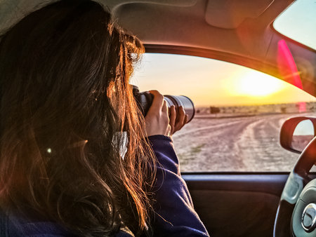 capture of a woman photographing the sunset from car