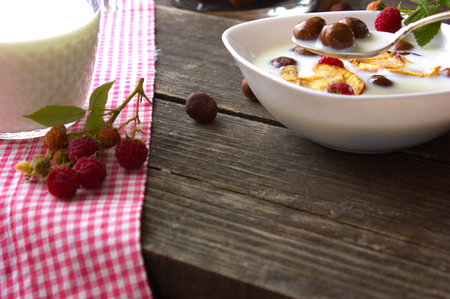 a plate with homemade chocolate balls, raspberries, milk and an apple on a table with a jug of milk