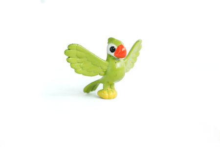 Green bird toy standing made of plastic on an isolated white background, can be used as a medium to introduce flying animals to childrenの写真素材