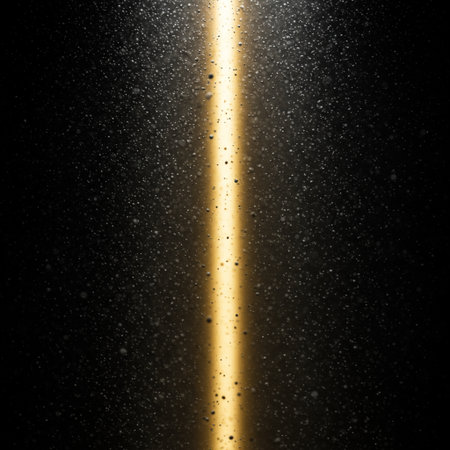 Gold light beam on a black background with some water droplets on itの素材