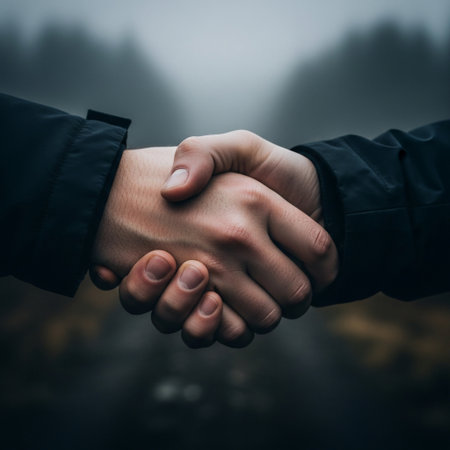 Close up of two men shaking hands on a road in the fogの素材