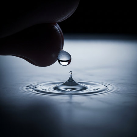 Finger and drop of water on black background. Shallow depth of field.の素材