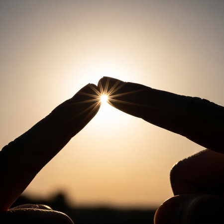 Silhouette of hands holding the sun in the sunset background.の素材