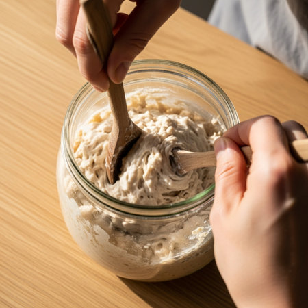 Woman's hands kneading dough with a wooden spoon, close upの素材