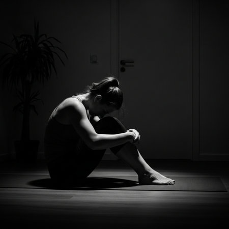 Young woman sitting on the floor in a dark room. Black and whiteの素材