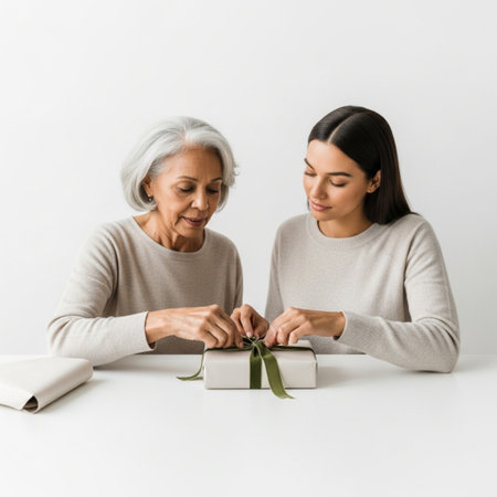 mother and daughter holding gift box and looking at each other isolated on whiteの素材