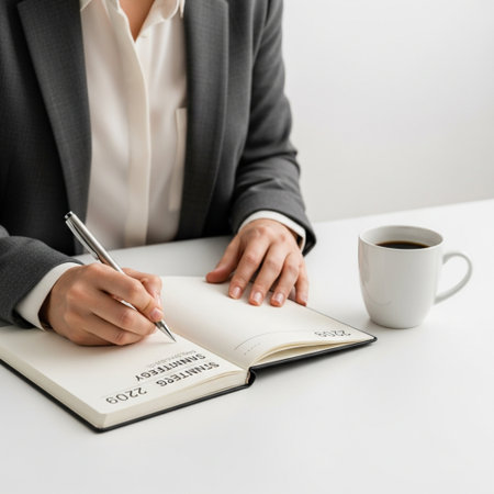 cropped view of businesswoman writing in diary at workplace with cup of coffeeの素材