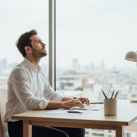 side view of handsome young businessman using laptop and looking away in officeの素材