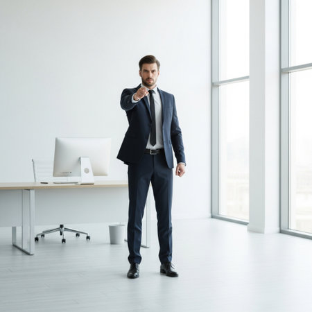 Full length portrait of confident businessman standing in office and looking at cameraの素材