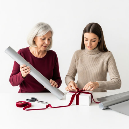 senior woman giving gift box to daughter at table with wrapping paperの素材