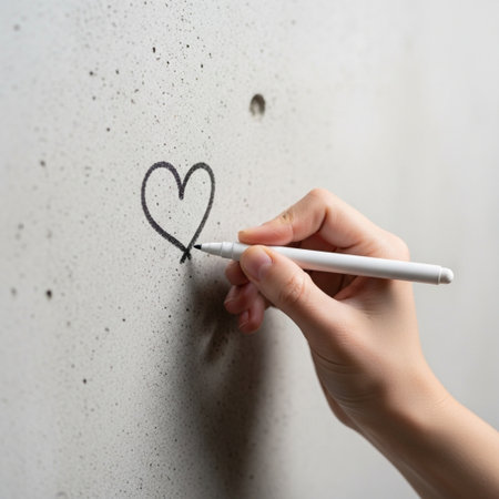 Hand drawing a heart on the wall with a white pencil. Close-up.の素材