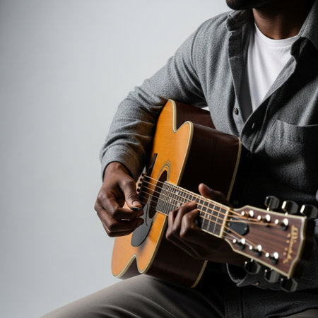 Close-up image of a man playing acoustic guitar on grey backgroundの素材