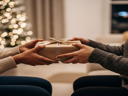 cropped shot of couple holding christmas gift box in living roomの素材
