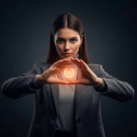 Young businesswoman making a heart shape with her hands on dark backgroundの素材