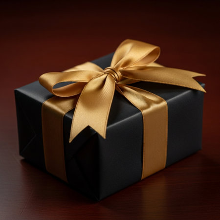 Black gift box with gold ribbon on wooden background. Close up.の素材