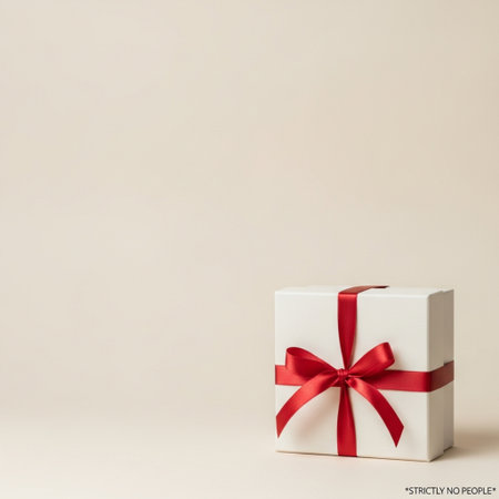 White gift box with red ribbon on beige background. Copy space.の素材