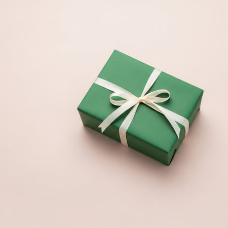Green gift box with white bow on pastel pink background. Flat lay.の素材