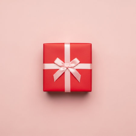 top view of red gift box with white bow isolated on pink backgroundの素材