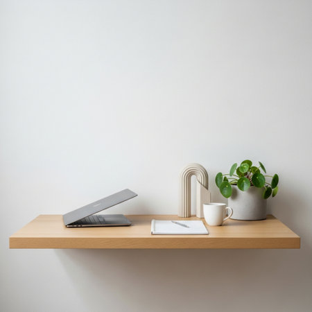 Wooden shelf with laptop, coffee cup and plant on white wall backgroundの素材