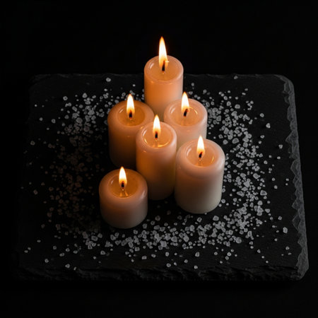 Burning candles on a black slate plate with sea salt on a black backgroundの素材