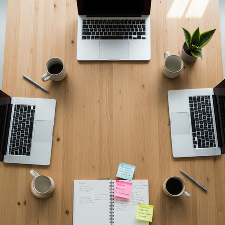 Top view of a wooden office desk with laptop computer, coffee cup, notepad and other itemsの素材