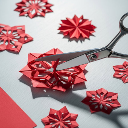 Scissors cut red paper snowflakes on a white background.の素材